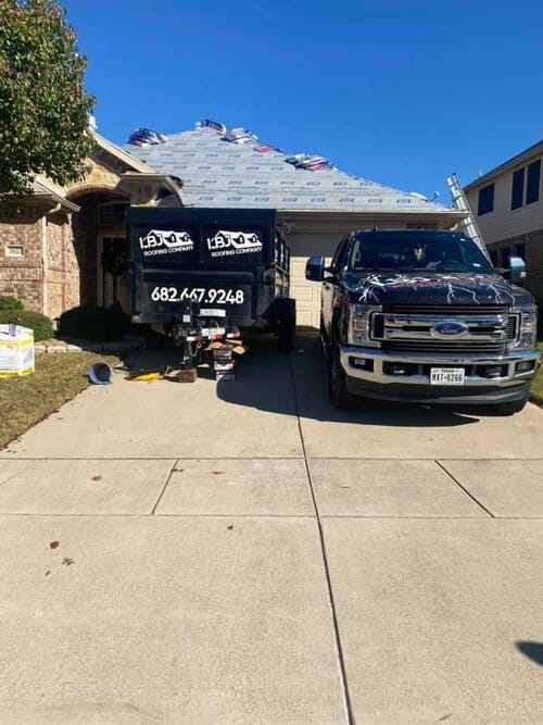 lbj roofing corp black truck and trailer parked in the driveway of a home doing roof repairs