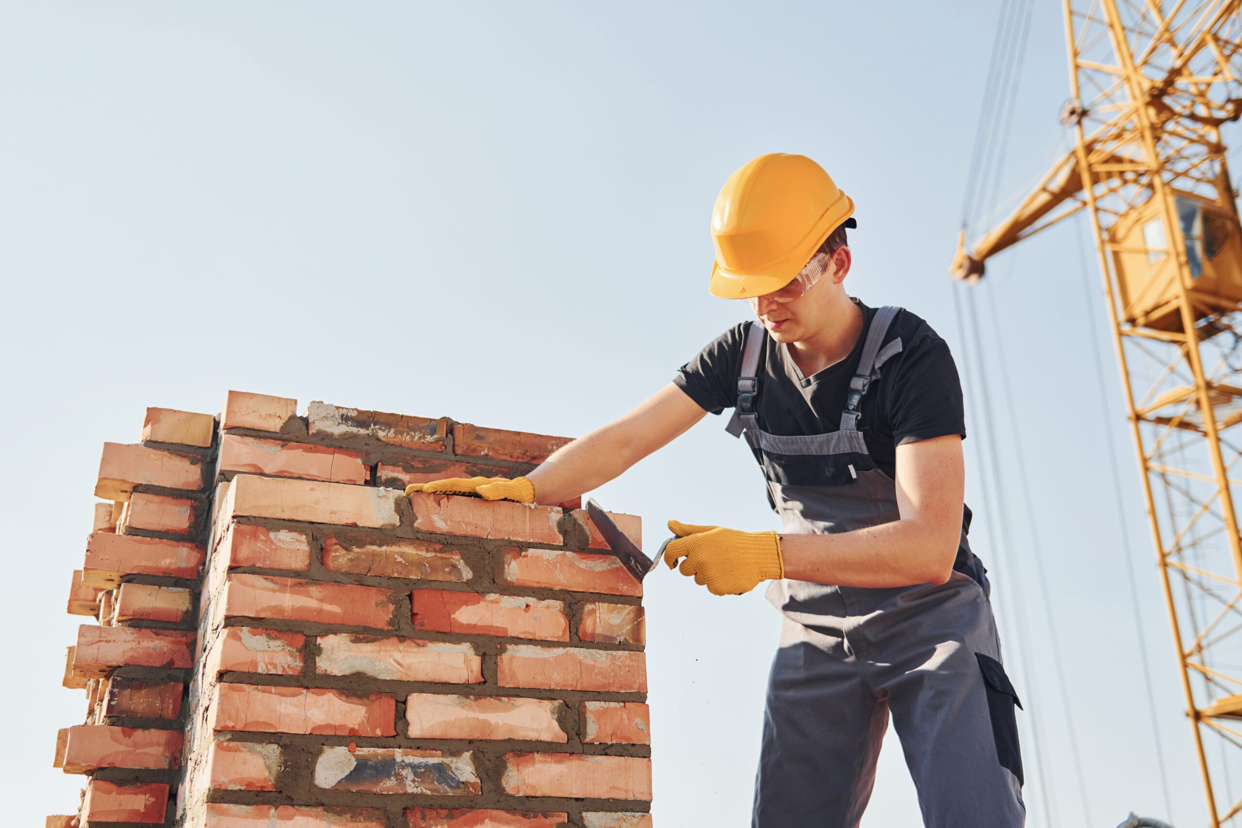 Installing brick wall. Construction worker in uniform and safety equipment have job on building.