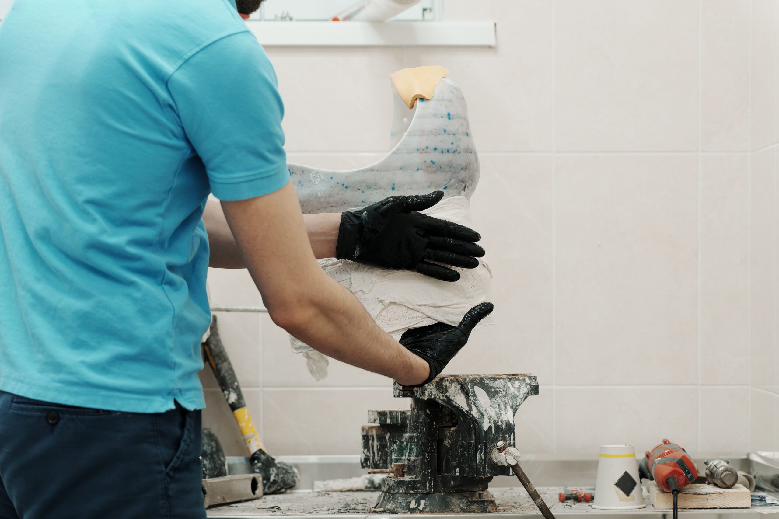 Closeup of crop unrecognizable male worker in black rubber gloves making hip disarticulation prosthesis mold with wet plaster in professional workshop