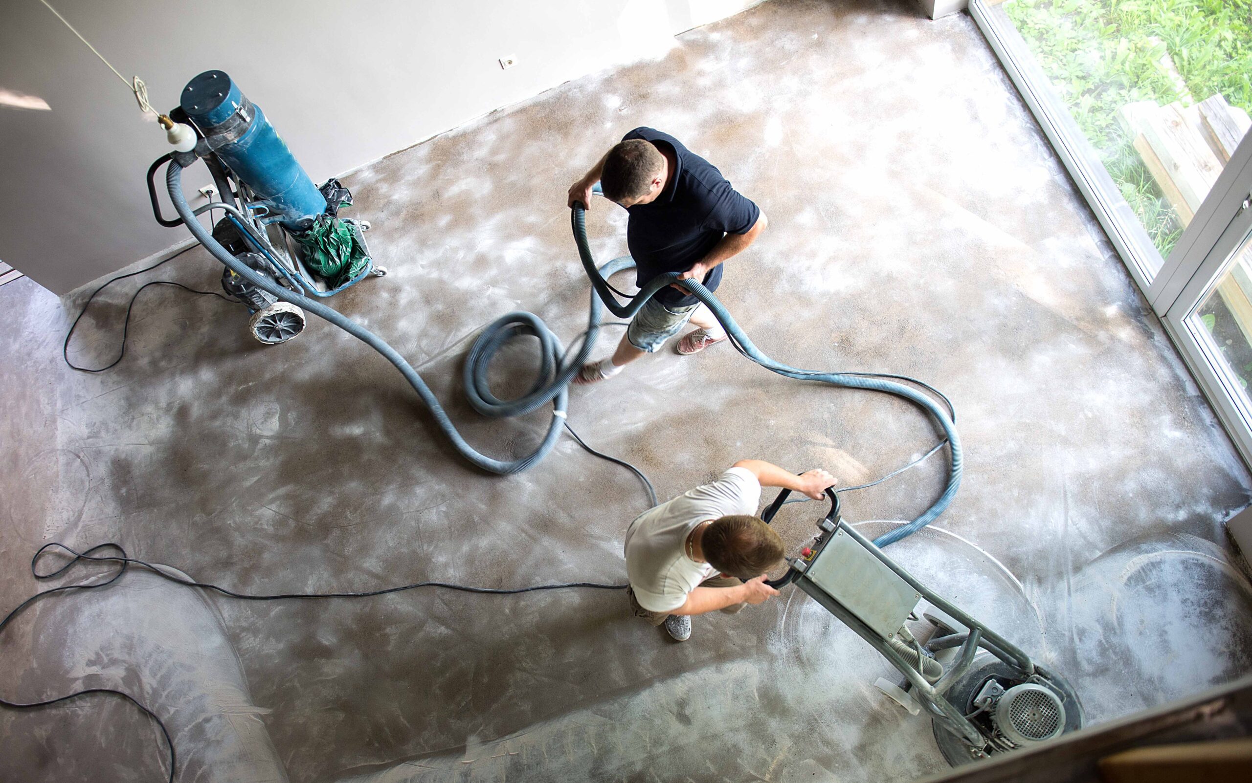 Construction worker in a family home living room that grind the concrete surface before applying epoxy flooring.Polyurethane and epoxy flooring.Concrete grinding.