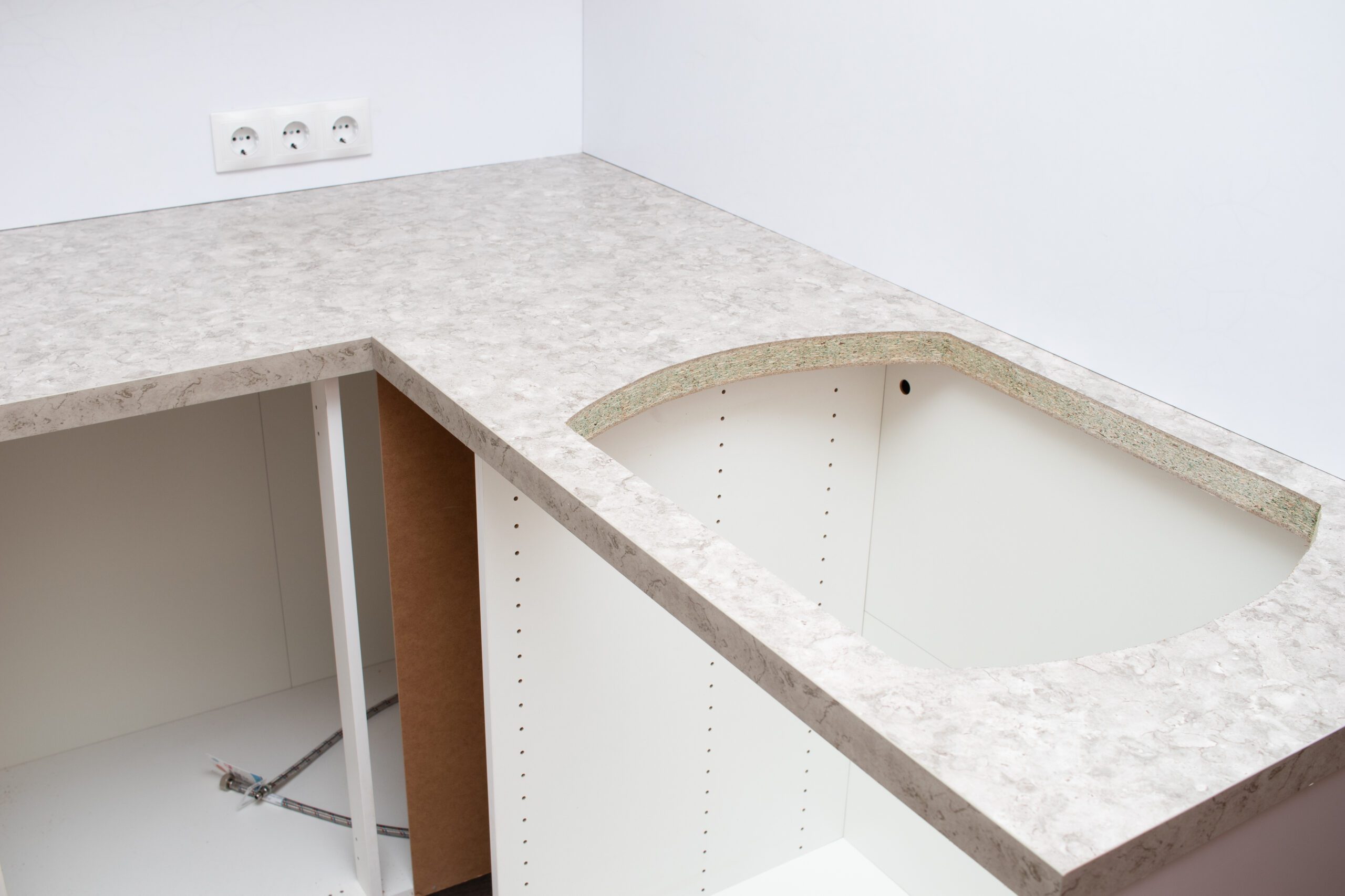 L-shaped kitchen countertop with sink cutout during initial installation phase