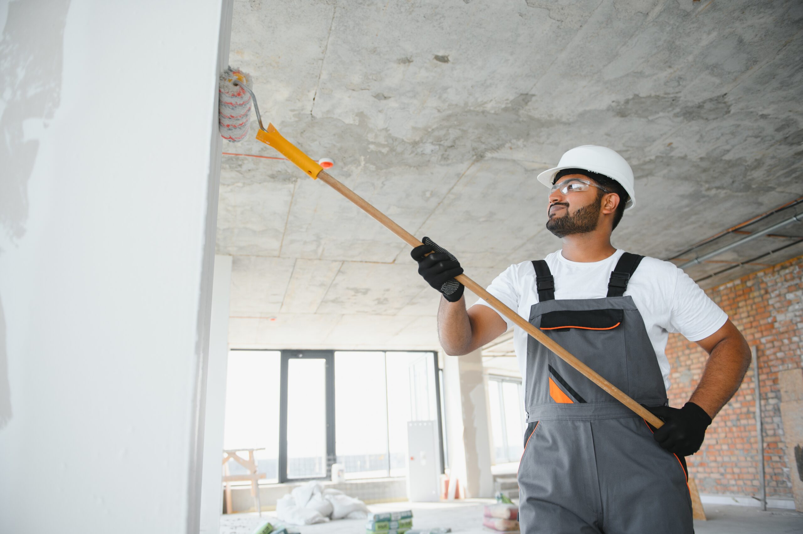 Contractor painting with roller as part of interior and exterior painting services in DFW