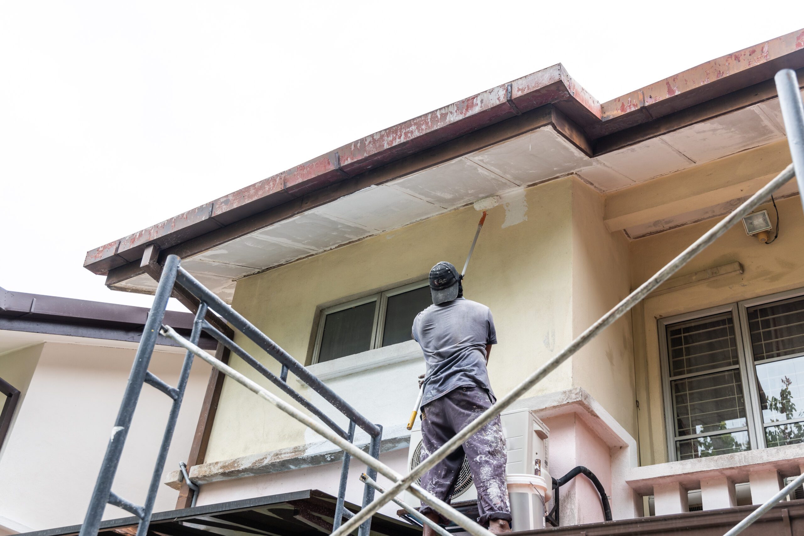 Exterior painter using roller on soffit during interior and exterior painting services in DFW