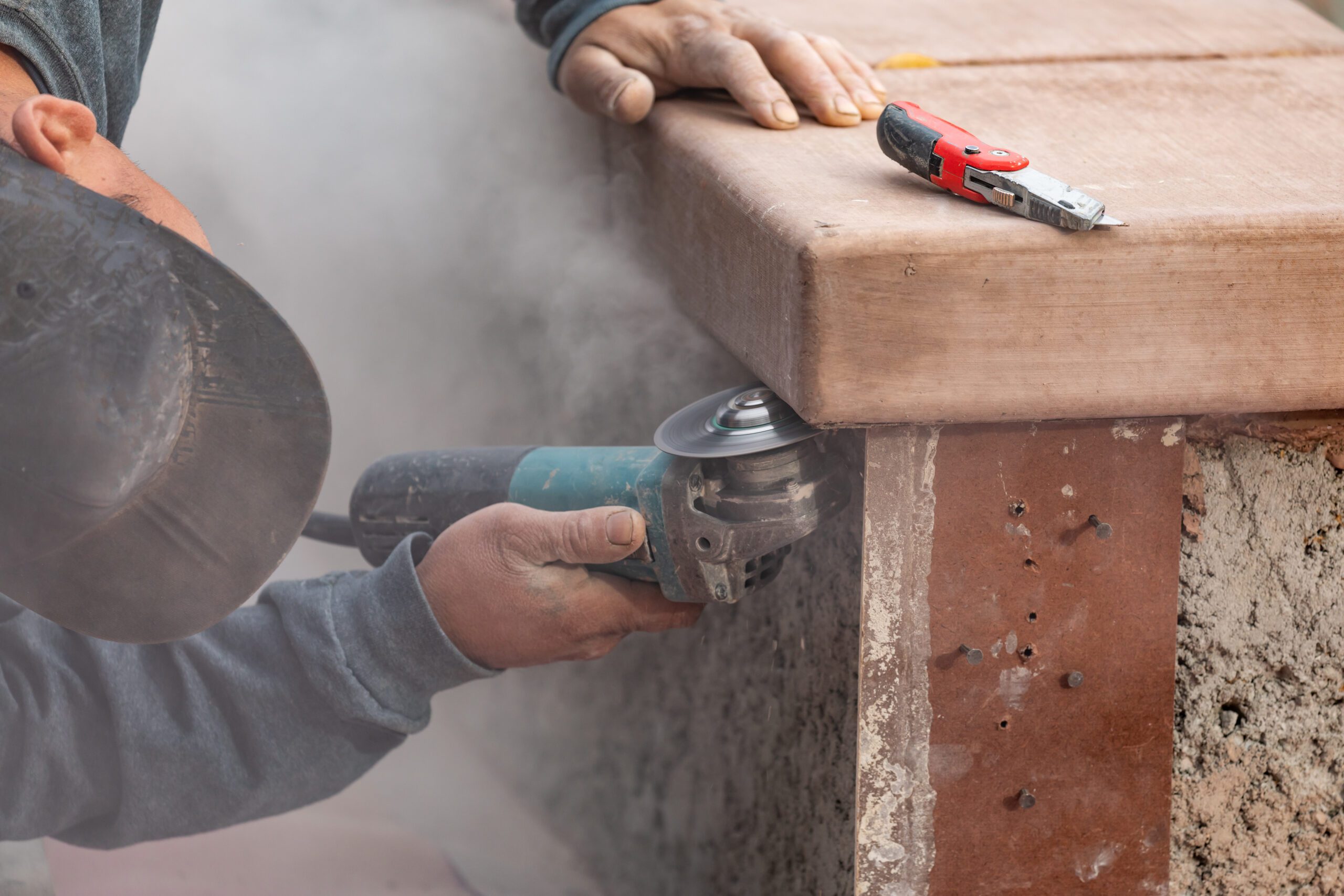 Construction worker using grinder on stone or concrete countertop with dust flying