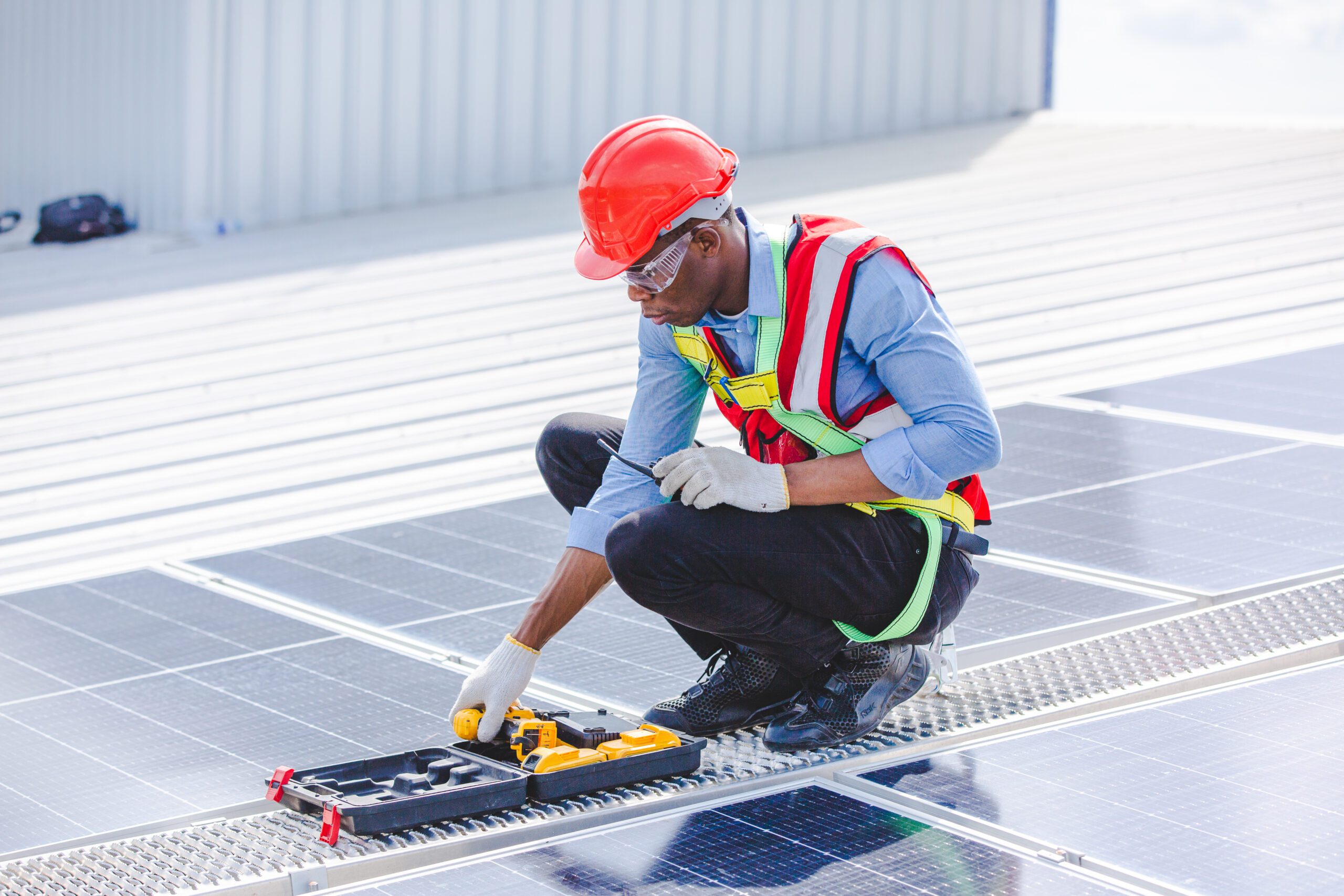 Solar Panel Installation in DFW - Maintenance Work - LBJ Roofing Company Corp. Engineer in red helmet performing maintenance on rooftop solar panels