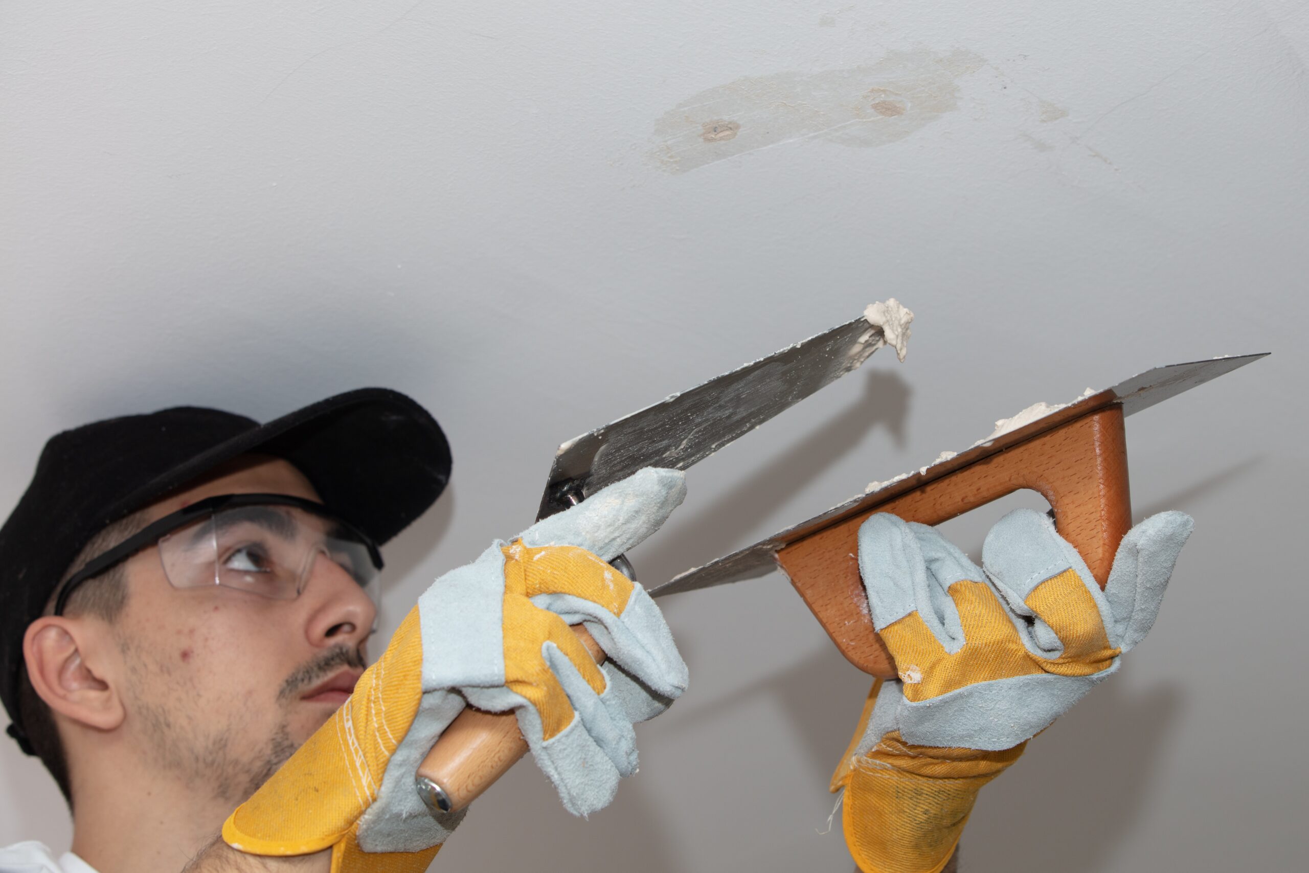 Texture Repair DFW - Wall Patch and Smooth Finish - LBJ Roofing Company Corp. Man applying patch plaster on ceiling with trowel