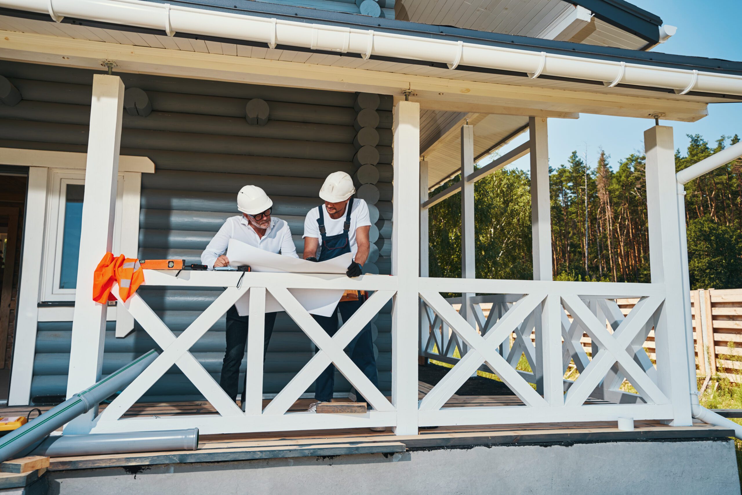 Contractors Planning Renovation Using Porch Services - LBJ Roofing Company Corp. Construction workers reviewing blueprints on a home’s porch, preparing upgrades through porch services.