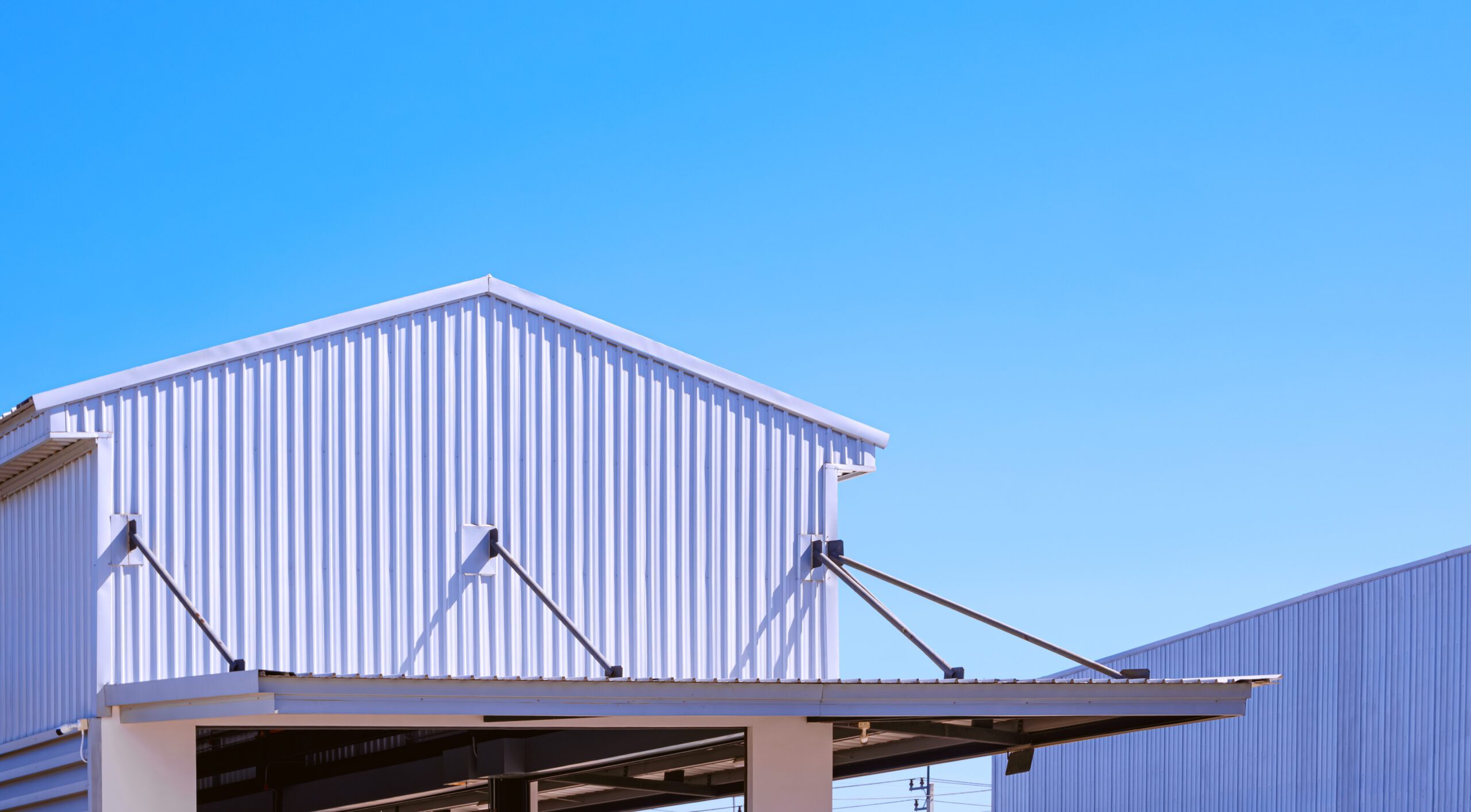 Modern industrial building featuring white corrugated metal roofing with structural supports