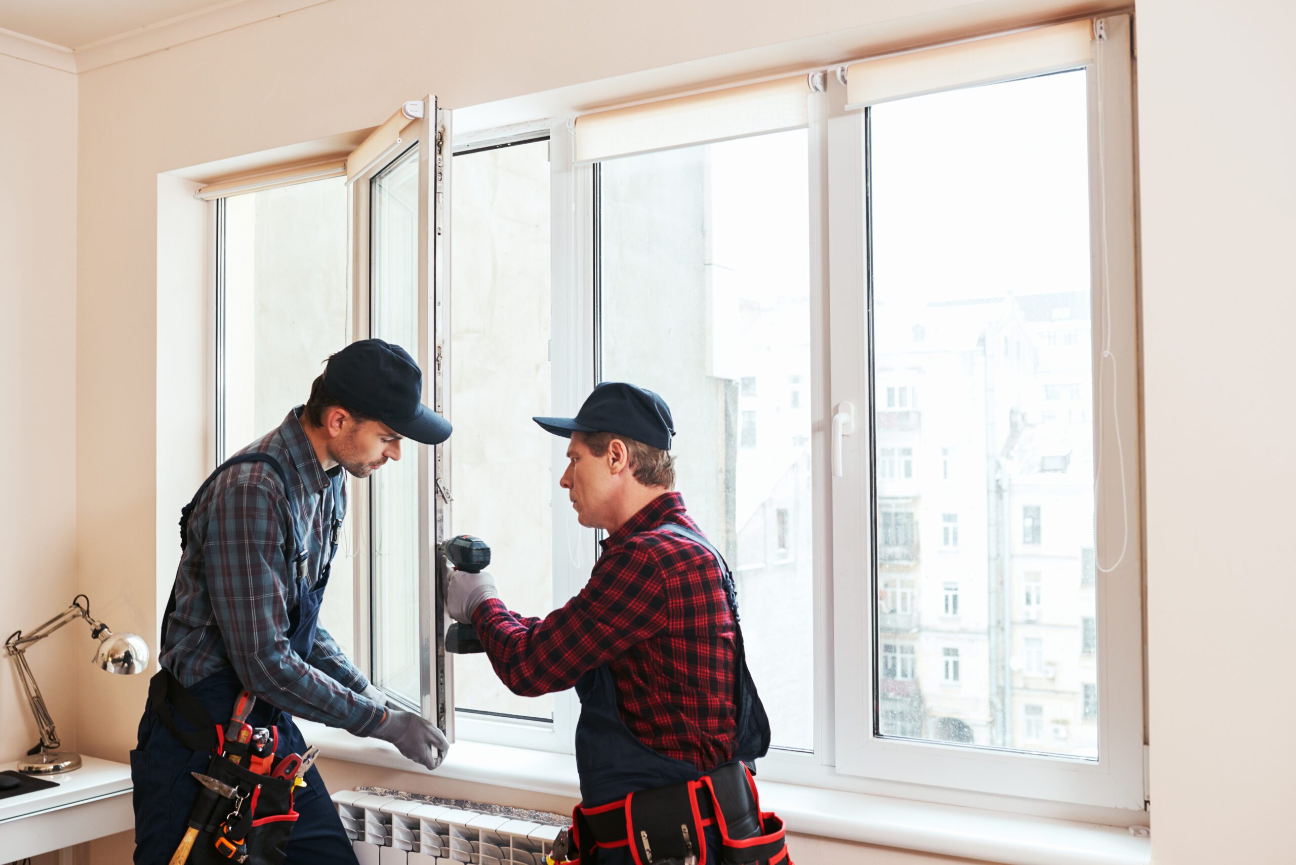 Team Installing New Windows Indoors - LBJ Roofing Company Corp. Two workers using tools for interior window installation and repair